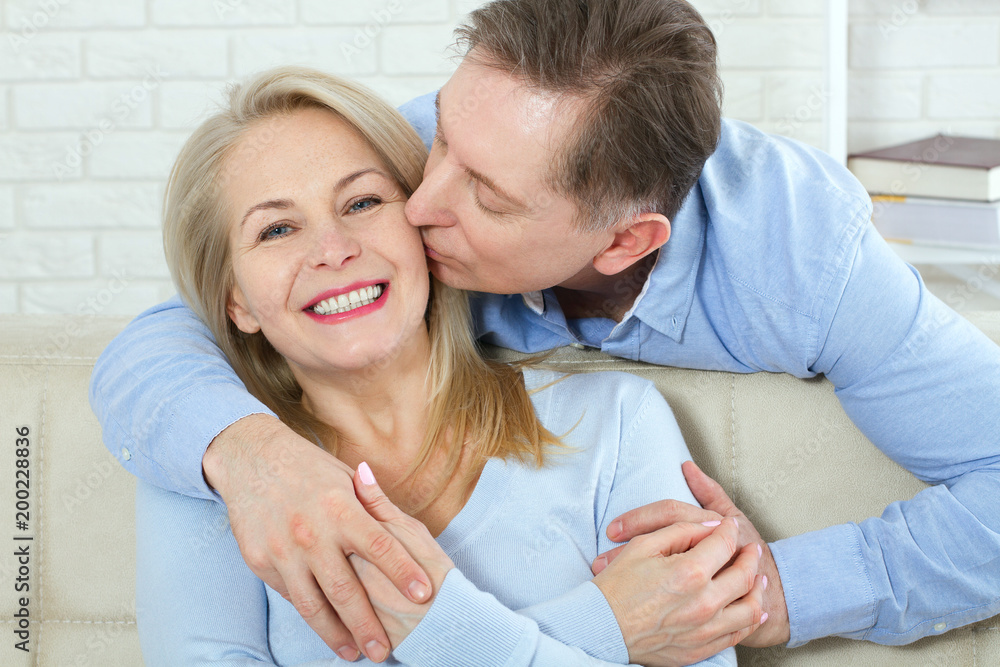 Fototapeta premium Close up photo of cheerful excited happy happily happy with toothy shining smile blond attractive woman and man, he hugs her from behind and kisses