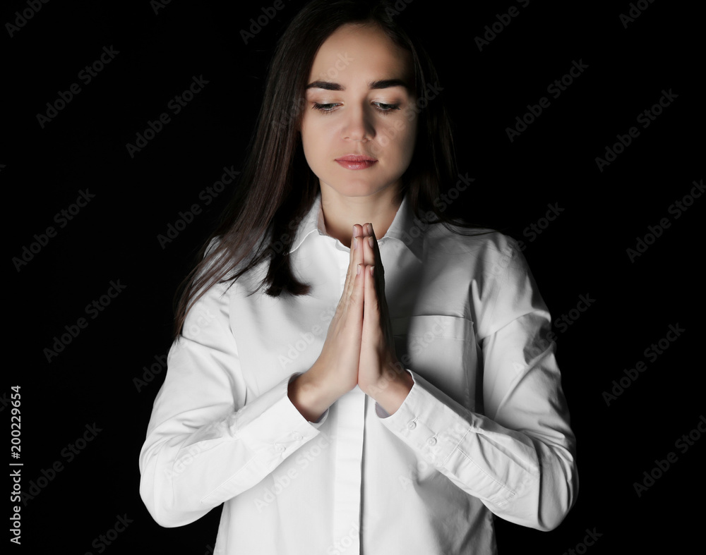 Religious young woman praying on black background Religious young woman praying on black background