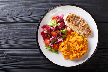 Delicious grilled chicken with garnish of sweet potato and fresh salad close-up on a plate. horizontal top view