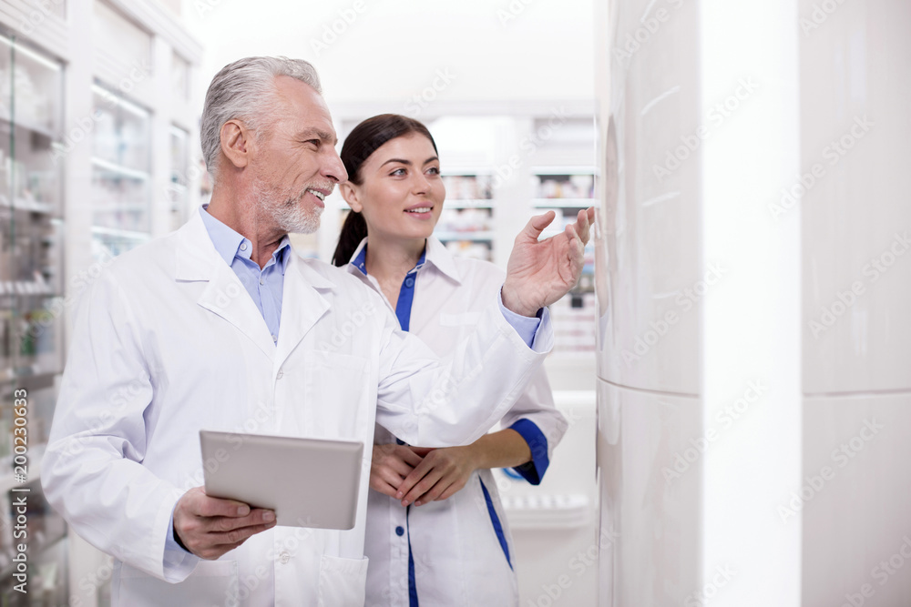 Meditative two pharmacists using tablet while working together Meditative two pharmacists using tablet while working together