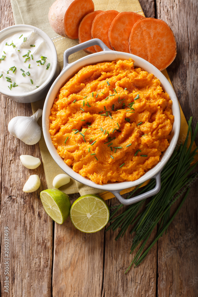 Freshly prepared mashed sweet potatoes with herbs, garlic and lime close up in a pot. Vertical top view Freshly prepared mashed sweet potatoes with herbs, garlic and lime close up in a pot. Vertical top view