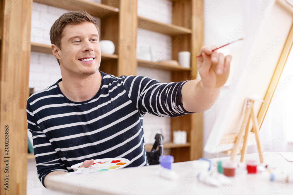 Inspired with art. Joyful invalid using brush while painting on canvas Inspired with art. Joyful invalid using brush while painting on canvas