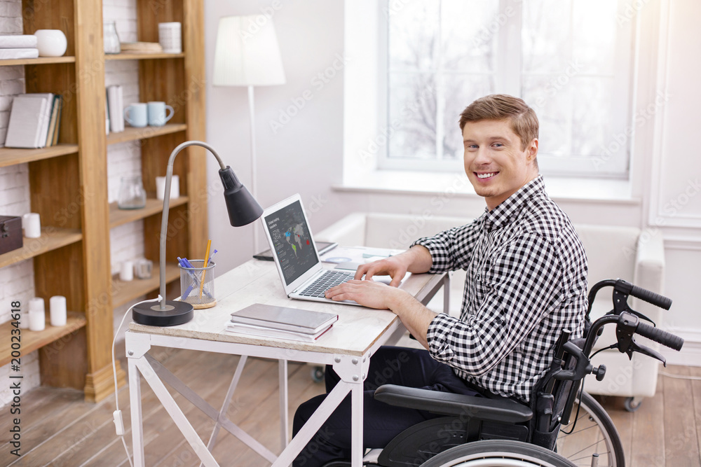 Follow my example. Cheerful IT man sitting in semi position while looking at camera Follow my example. Cheerful IT man sitting in semi position while looking at camera