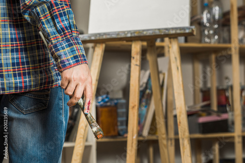 Closeup of a male artist holding a paintbrush in his hand