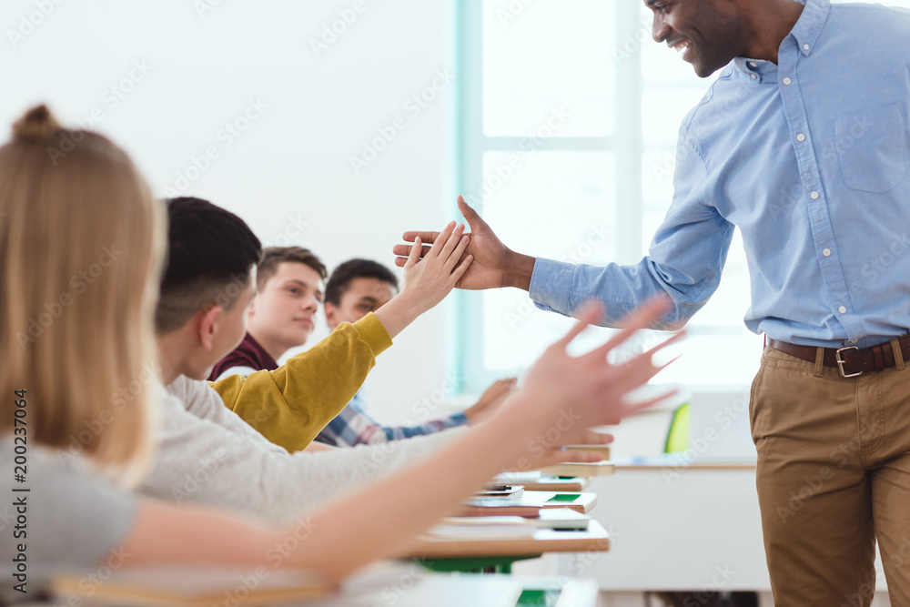Cropped image of african american taking high five to multicultural high school teenage students Cropped image of african american taking high five to multicultural high school teenage students