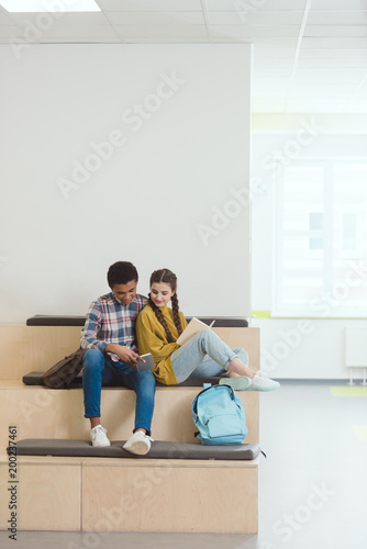 high school students couple doing homework at school corridor together