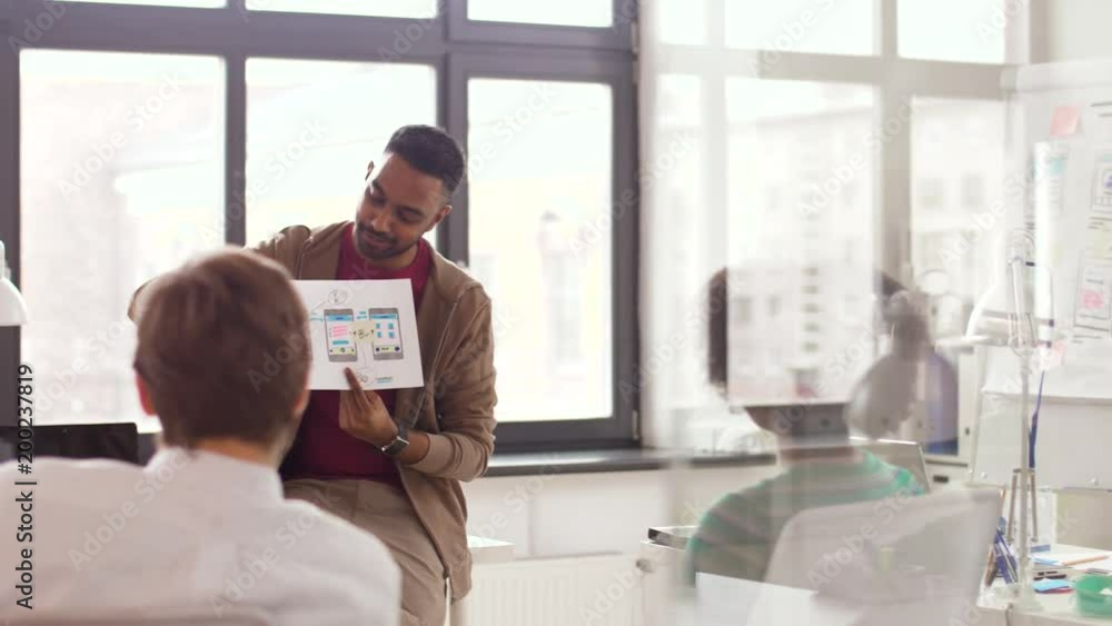 business, technology and software development concept - man showing user interface mockup to creative team at office business, technology and software development concept - man showing user interface mockup to creative team at office