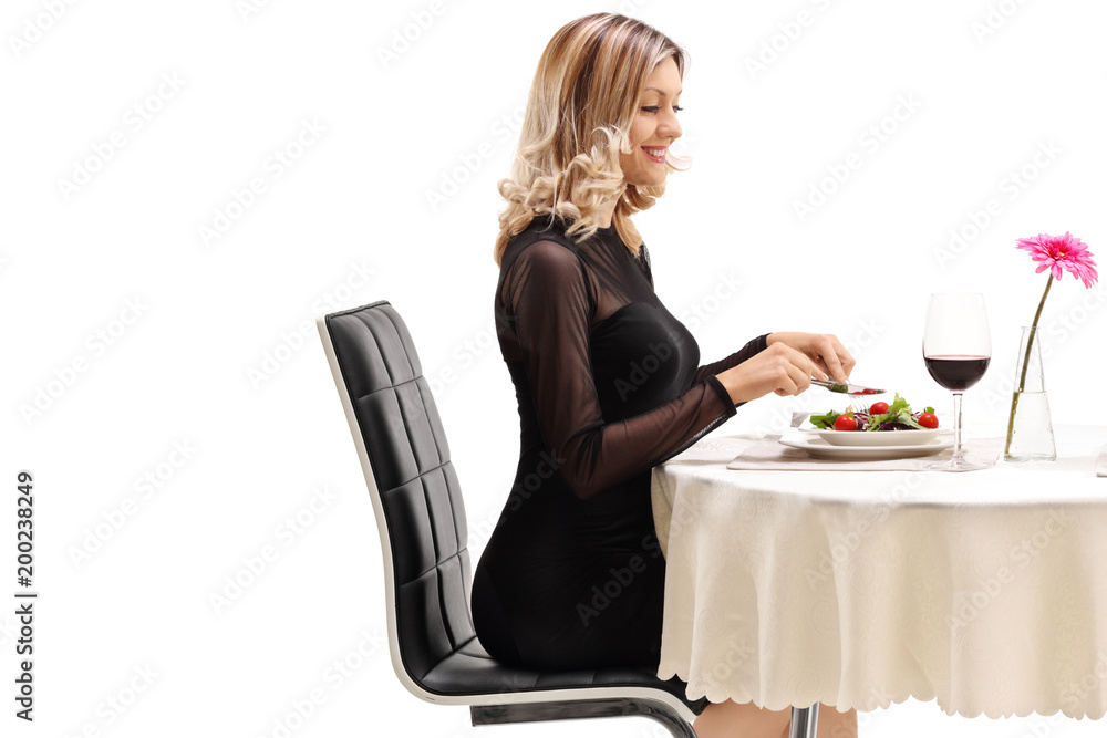 Young woman sitting at a restaurant table and eating Young woman sitting at a restaurant table and eating