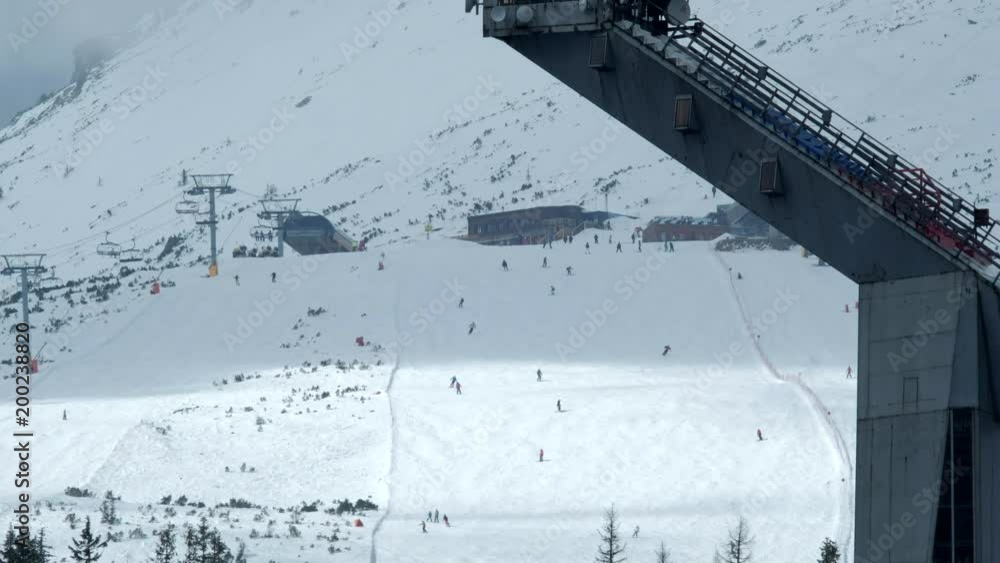 Close-up view of slope on the skiing resort. Skiers enjoying snowy slopes in high mountains. Close-up view of slope on the skiing resort. Skiers enjoying snowy slopes in high mountains.