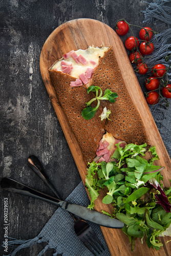 Black wheat and wheat galette topped with cooked ham and emmental cheese