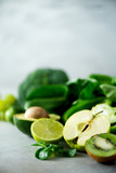 Organic green vegetables and fruits on grey background. Copy space. Green apple, lettuce, cucumber, avocado, kale, lime, kiwi, grapes, banana, broccoli