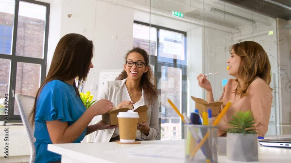 business lunch and people concept - happy businesswomen eating take out food at office business lunch and people concept - happy businesswomen eating take out food at office