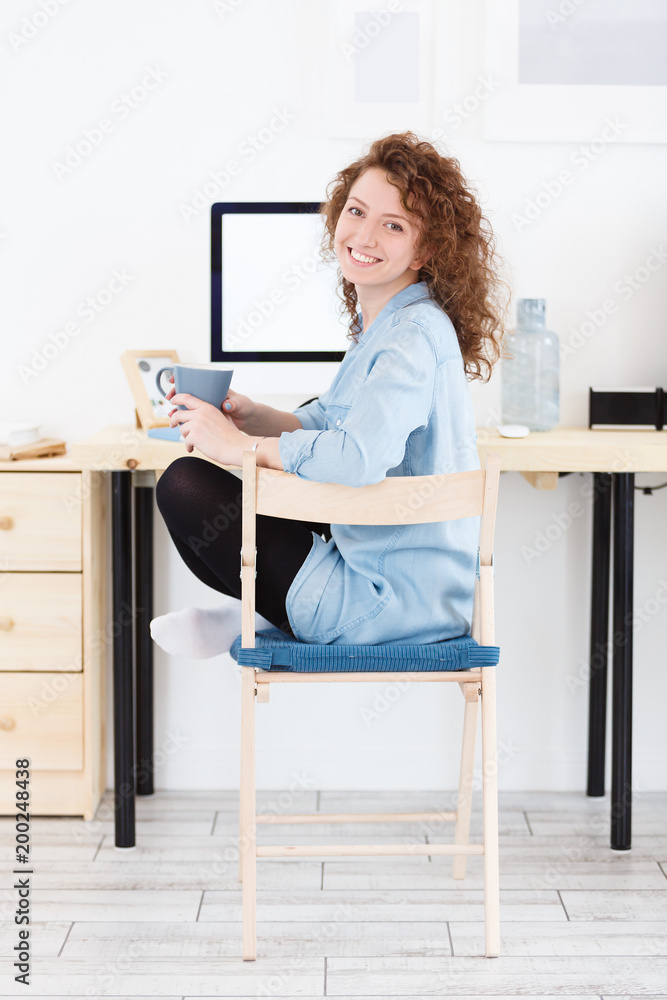Happy and joyful redhead student uses modern technologies for communication on computer, looking and smiling at the camera during preparation for exams Happy and joyful redhead student uses modern technologies for communication on computer, looking and smiling at the camera during preparation for exams