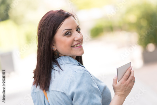 Portrait of happy young woman holding her mobile phone