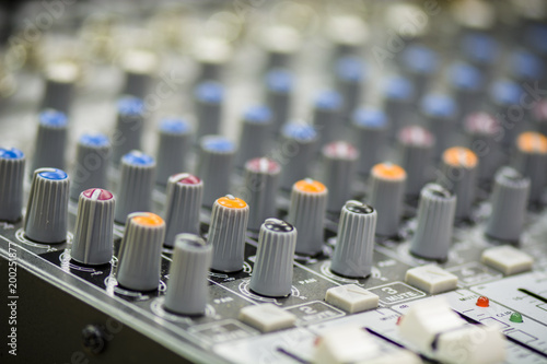 Close up of a mixing console with sliders and buttons.