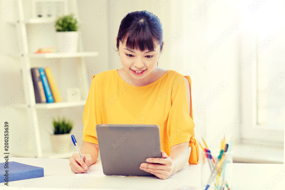 people, education, high school and learning concept - happy asian young woman student with tablet pc computer, book and notepad writing at home people, education, high school and learning concept - happy asian young woman student with tablet pc computer, book and notepad writing at home
