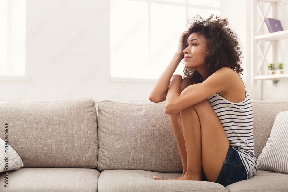 Sad african-american woman on couch at home Sad african-american woman on couch at home