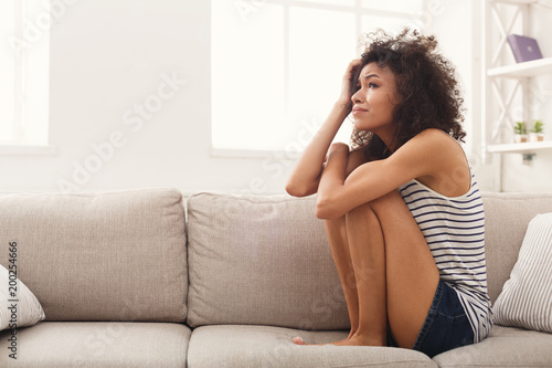Sad african-american woman on couch at home