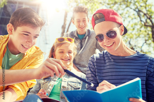 education, high school and people concept - group of happy teenage students with notebooks learning at campus yard