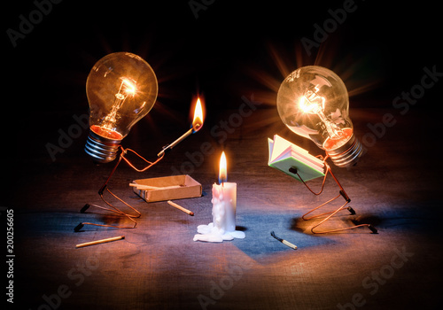 Art composition on the topic of teaching, development or education. Two light bulbs in the form of people near a burning candle
