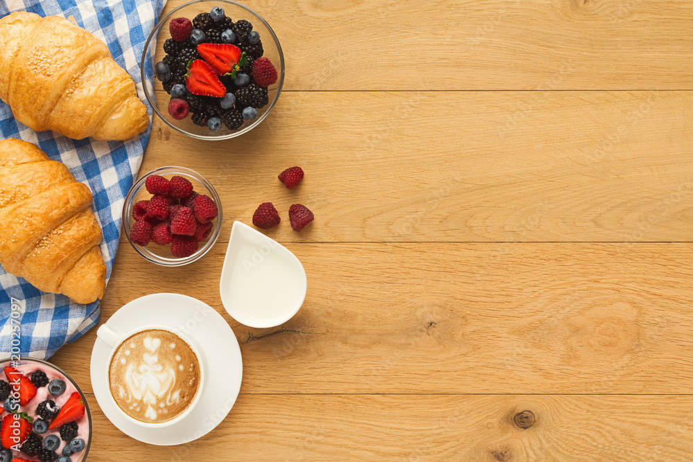 Continental breakfast with croissants and berries on natural woo Continental breakfast with croissants and berries on natural woo