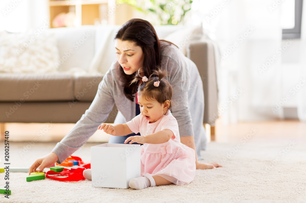 family, holidays and people concept - mother and happy little daughter playing with toy or gift box at home family, holidays and people concept - mother and happy little daughter playing with toy or gift box at home