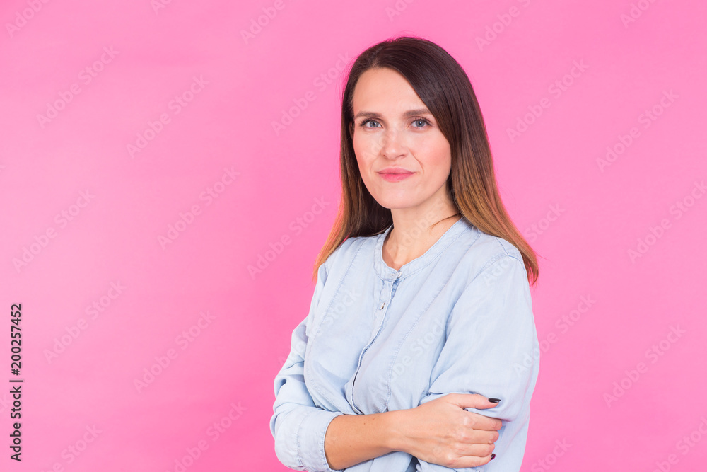 Portrait of a beautiful woman with long brown hair wearing blue cotton blouse, standing waist up smiling on a pink background Portrait of a beautiful woman with long brown hair wearing blue cotton blouse, standing waist up smiling on a pink background