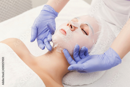 Woman gets face mask by beautician at spa