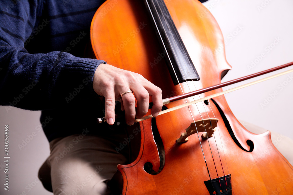 Man with cello in room with wall Man with cello in room with wall