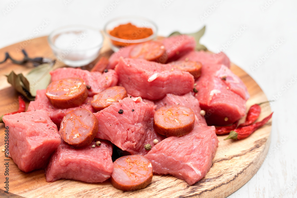 raw meat with smoked sausage on wooden board