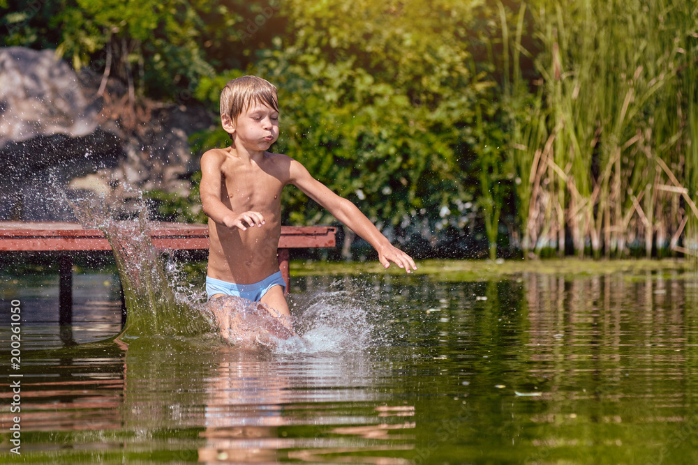Little boy having fun and jumping into the river from pier Little boy having fun and jumping into the river from pier
