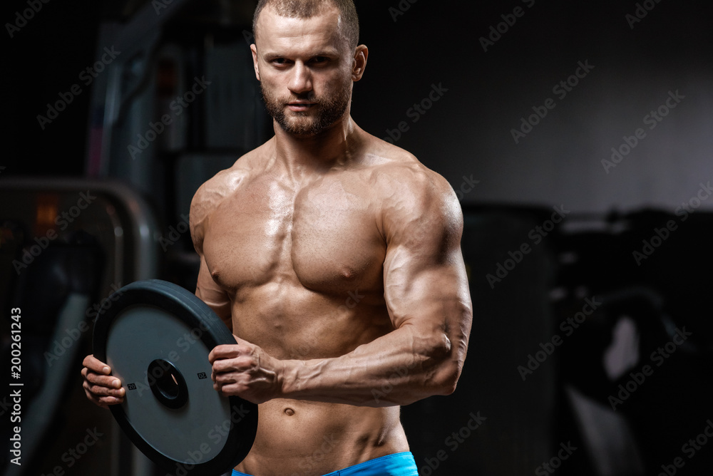 Strong athletic young man holding weightlifting plate