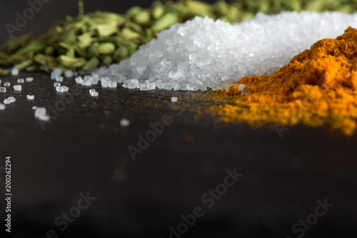 piles of spices of turmeric, fennel and sea salt on the stone surface are large