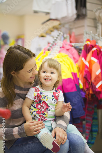 Happy woman with little daughter at garment supermarket