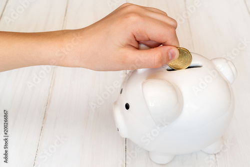 Child's hand putting a coin into piggy bank