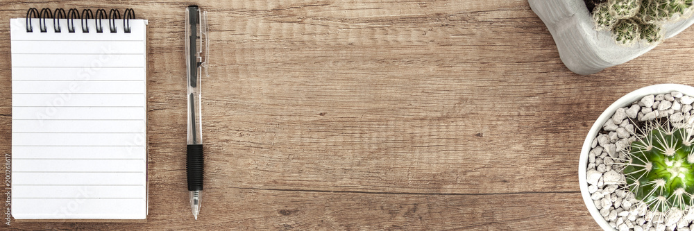 Wooden desk with a notebook and plants arranged in a row Wooden desk with a notebook and plants arranged in a row