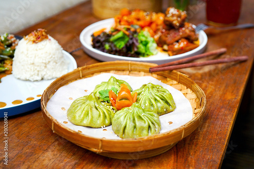 Juicy veggie bun (green dumplings) on a wood plate and on a wooden table. Chinese food in Bali restaurant. Top view with copy space.