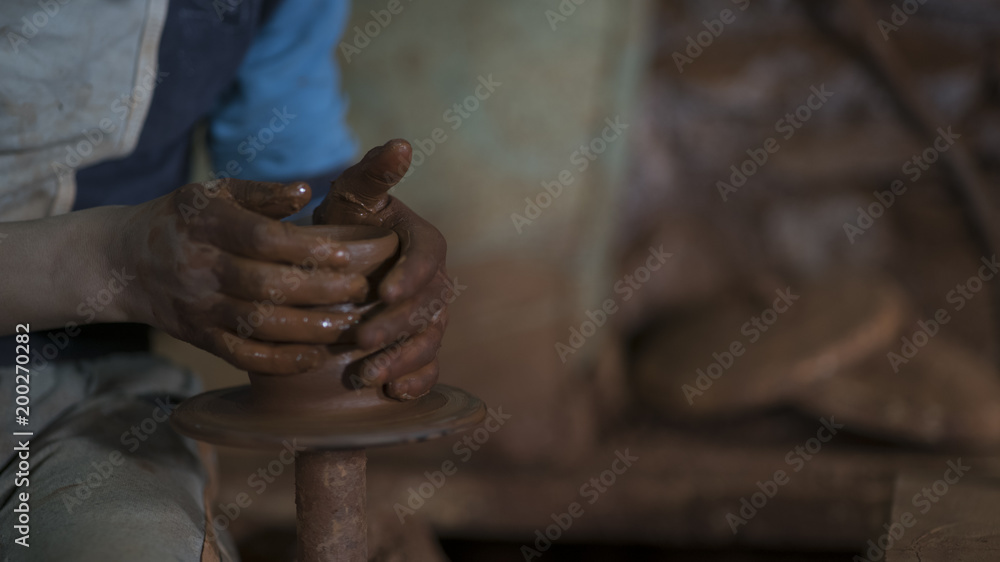 pottery, workshop, ceramics art concept - closeup on young ceramist hands with unbaked clay jug, craftsman stand at a workplace, hands holds the clay cup and tools