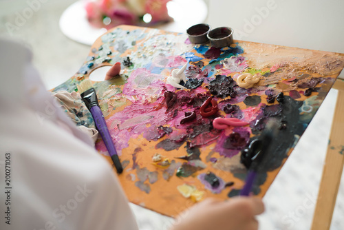 girl artist mixes oil paints on a palette