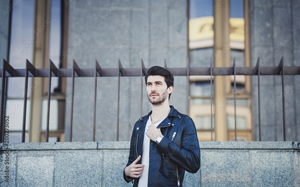 Outdoor portrait of stylish young man wearing leather jacket