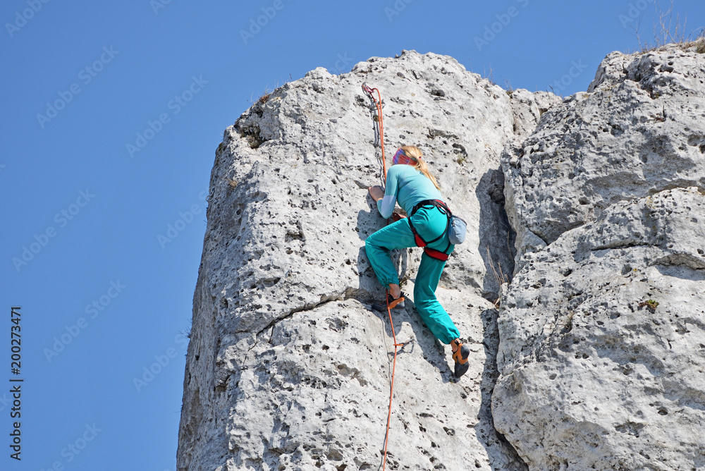 A woman climbing the rocks. - obrazy, fototapety, plakaty 
