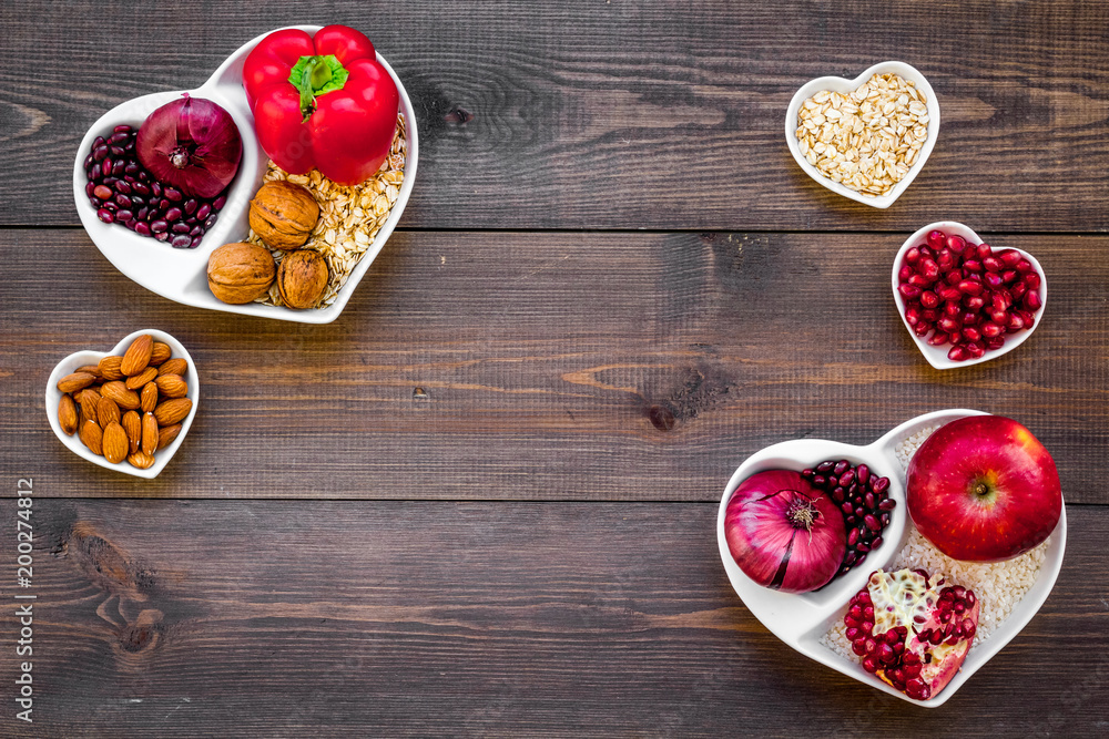 Food which help heart stay healthy. Vegetables, fruits, nuts in heart shaped bowl on dark wooden background top view copy space Food which help heart stay healthy. Vegetables, fruits, nuts in heart shaped bowl on dark wooden background top view copy space