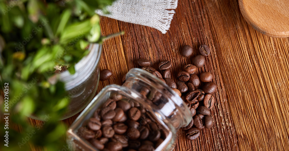 Roasted coffee beans get out of overturned glass jar on wooden background, selective focus, side view Roasted coffee beans get out of overturned glass jar on wooden background, selective focus, side view