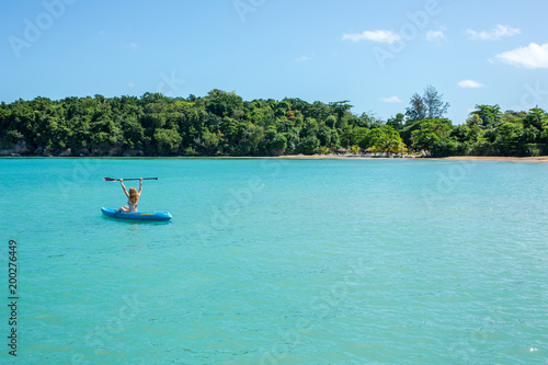 Eine junge Frau paddelt in einem Kajak auf dem Meer in der Karibik auf Jamaika 