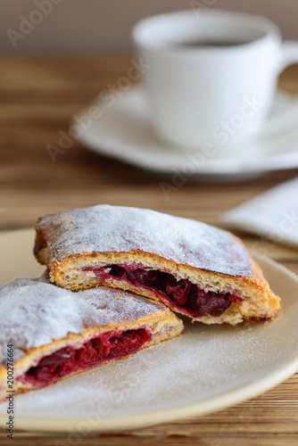 slices of strudel from puff pastry with a cup of tea on a wooden table