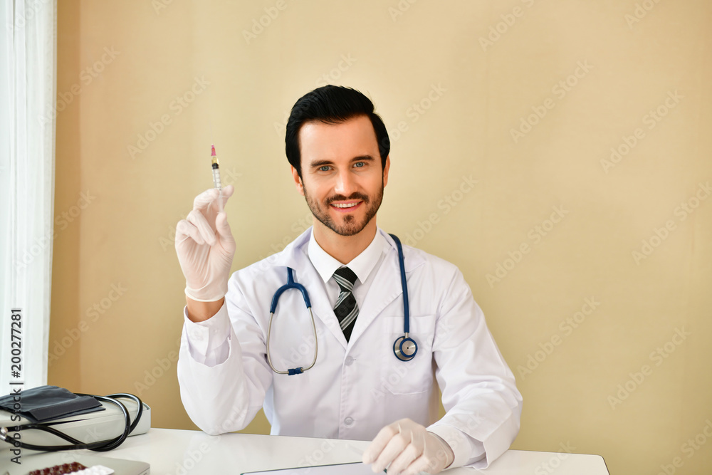 Smiling doctor posing in the office, he is wearing a stethoscope, medical staff on the hospital background Smiling doctor posing in the office, he is wearing a stethoscope, medical staff on the hospital background
