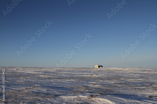 Lonely cabin along an arctic landscape with snow on the ground, near Arviat Nunavut Canada
