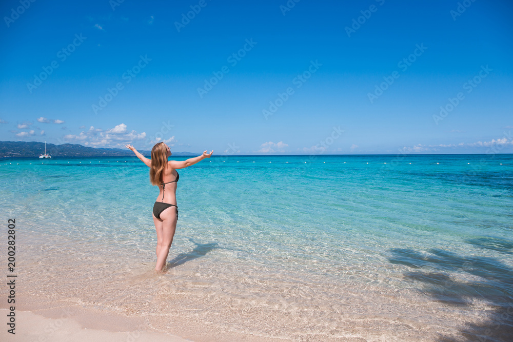 Eine junge Frau spaziert am Strand in der Karibik auf Jamaika
