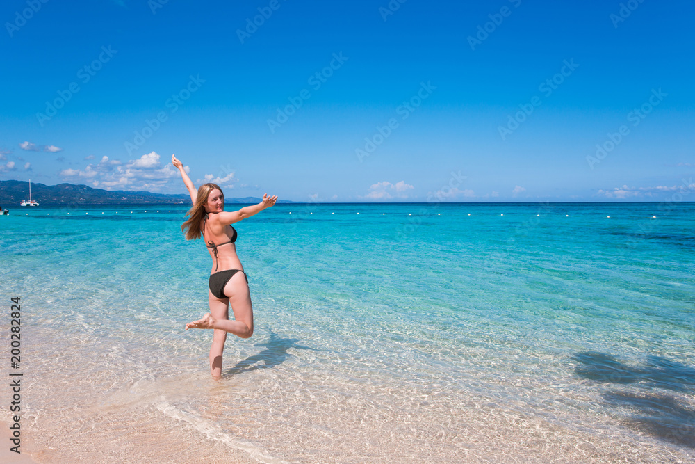 Eine junge Frau spaziert am Strand in der Karibik auf Jamaika
