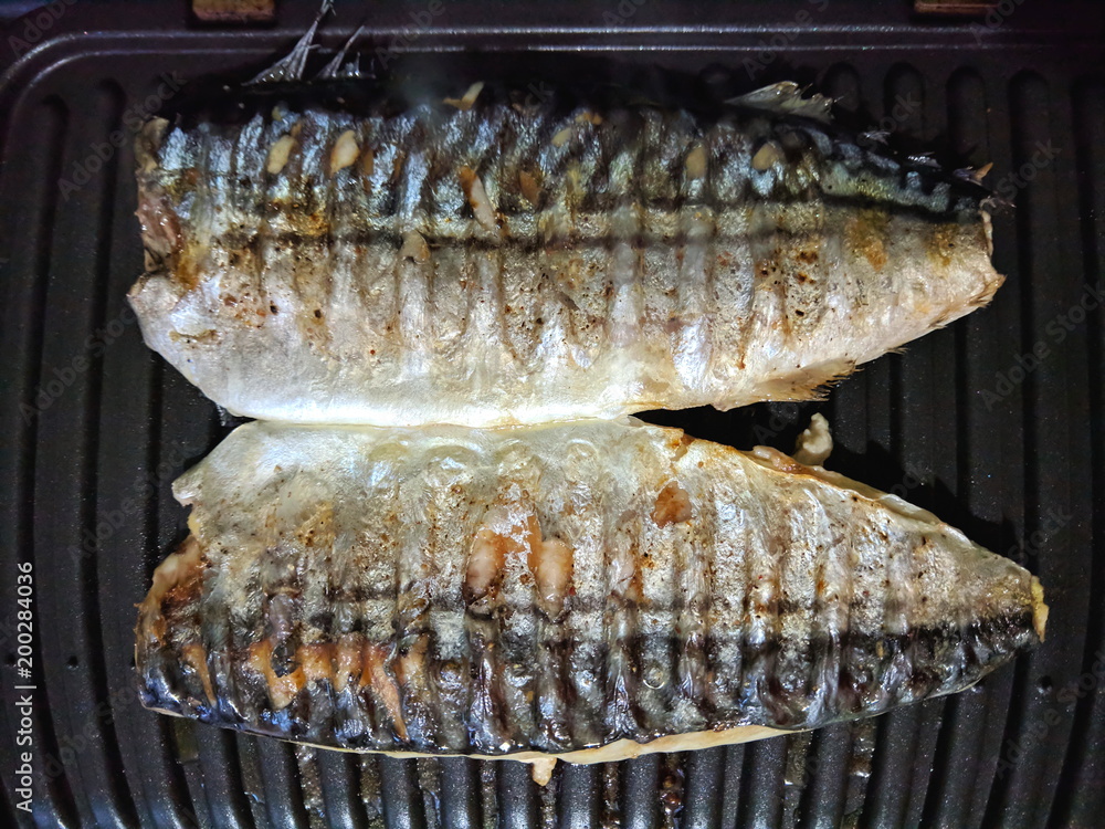Mackerel cooked on grill, fish with golden baked crust, homemade cuisine, black grilled surface, Asian cuisine, fried fish on holiday table, retro style food Mackerel cooked on grill, fish with golden baked crust, homemade cuisine, black grilled surface, Asian cuisine, fried fish on holiday table, retro style food